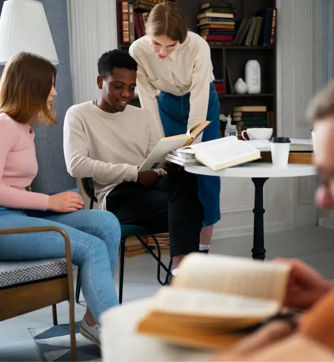 a man reading in a chair with two women reading over his shoulder